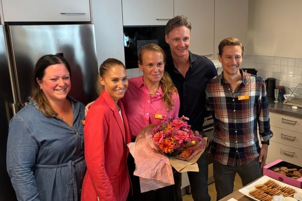 Verksamhetschef med blommor i handen, omgiven av personer från Attendos ledning.