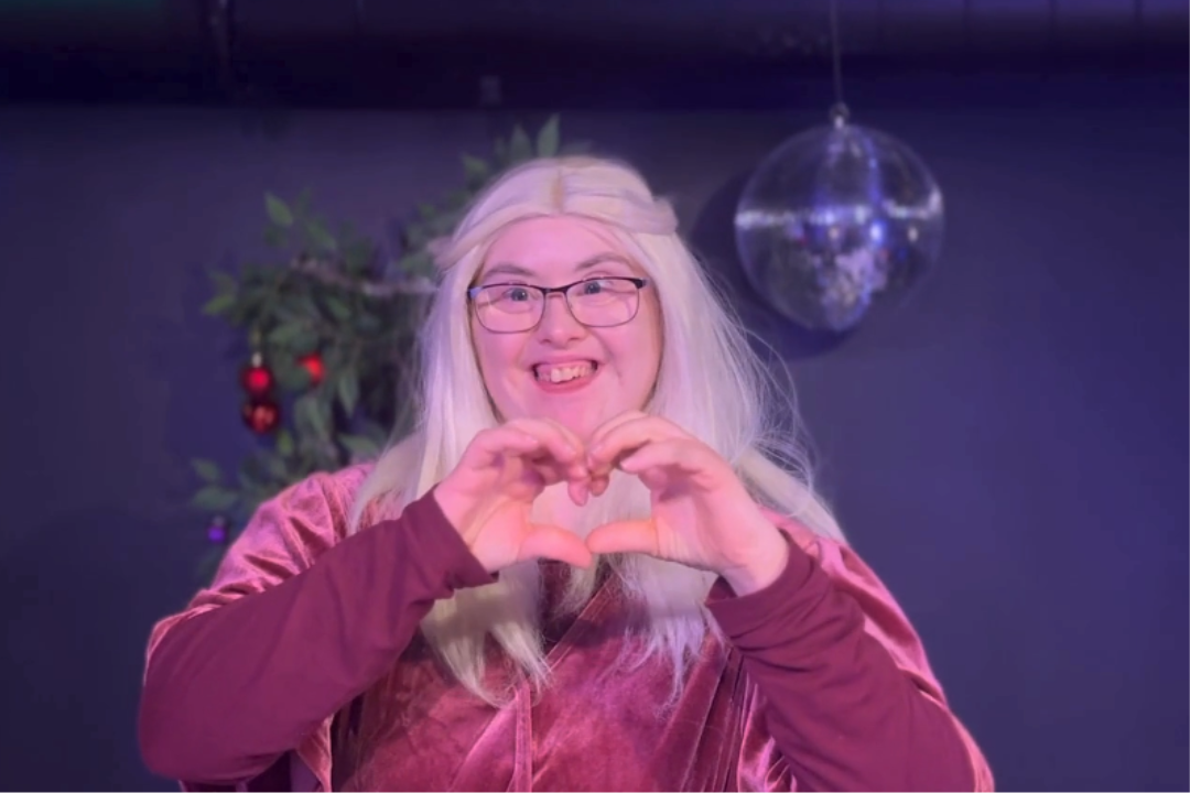 En deltagare från ett av våra DV ler, och gör hjärttecken med händerna