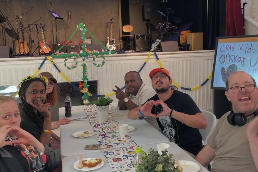 Deltagare på daglig verksamhet sitter runt ett dukat midsommarbord