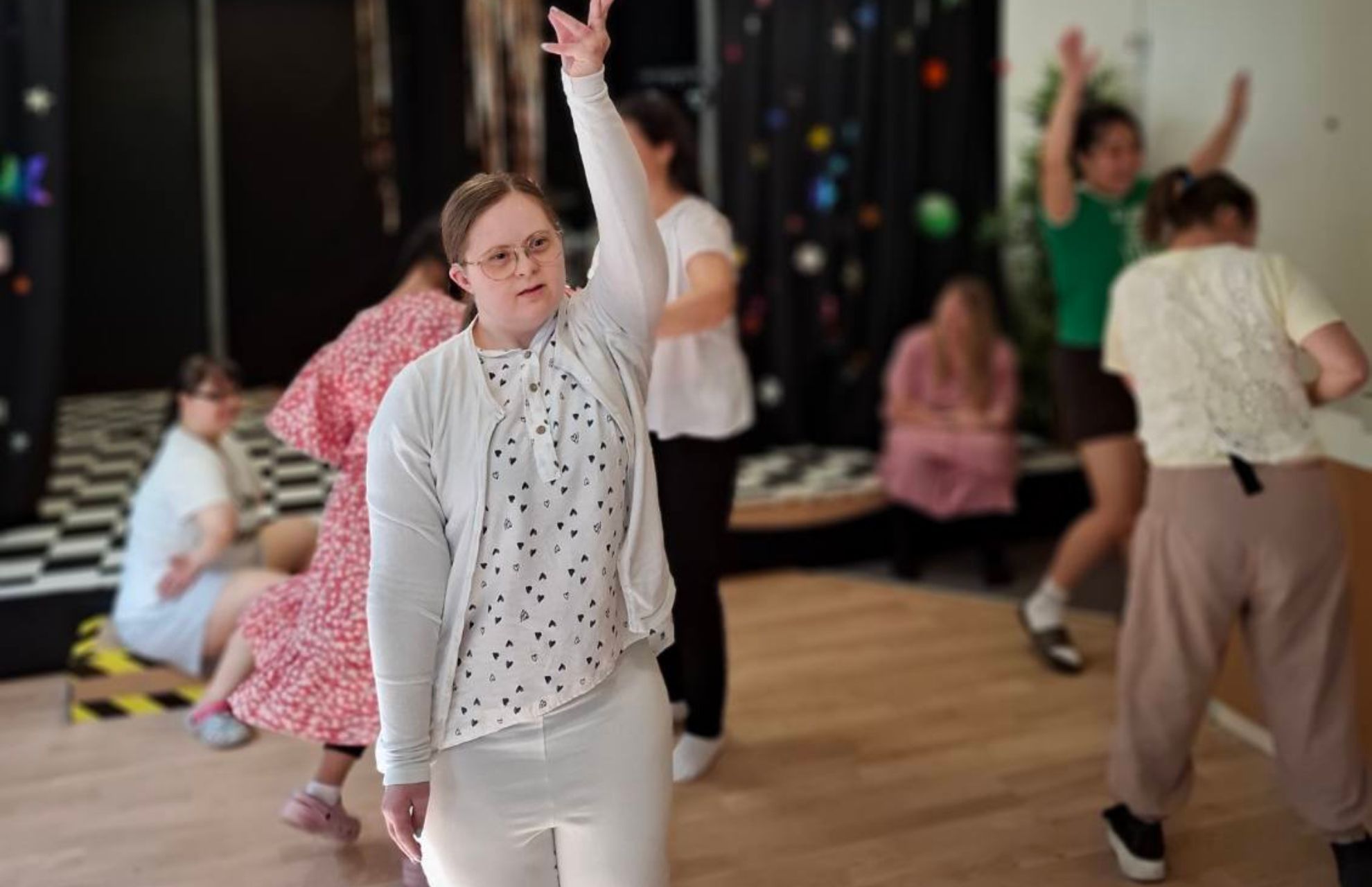 En grupp av deltagare på daglig verksamhet som dansar energiskt i en träningssal