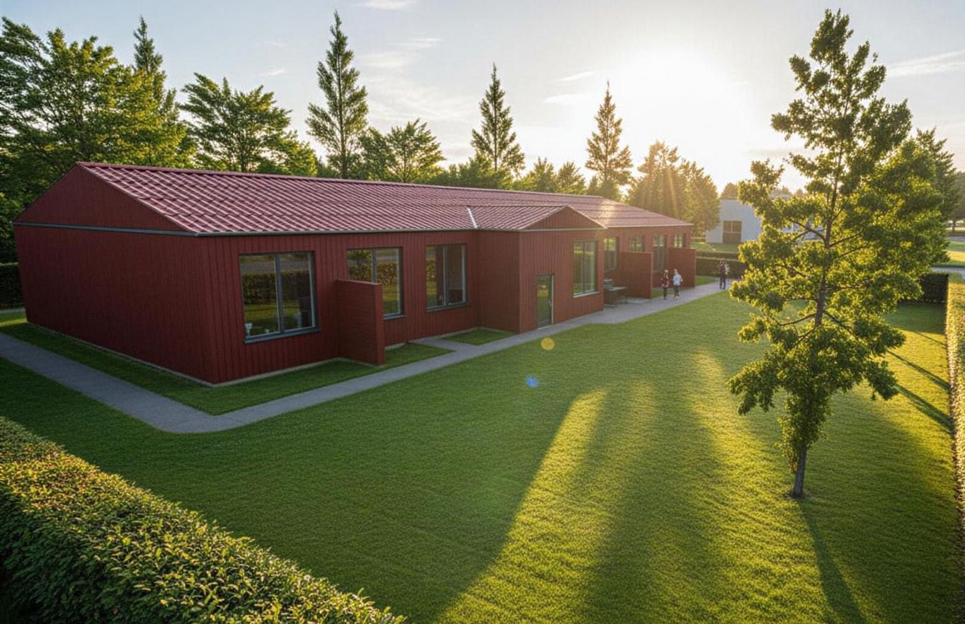 Visionsbild av rött hus med mycket grönska omkring, solen går ner bakom huset